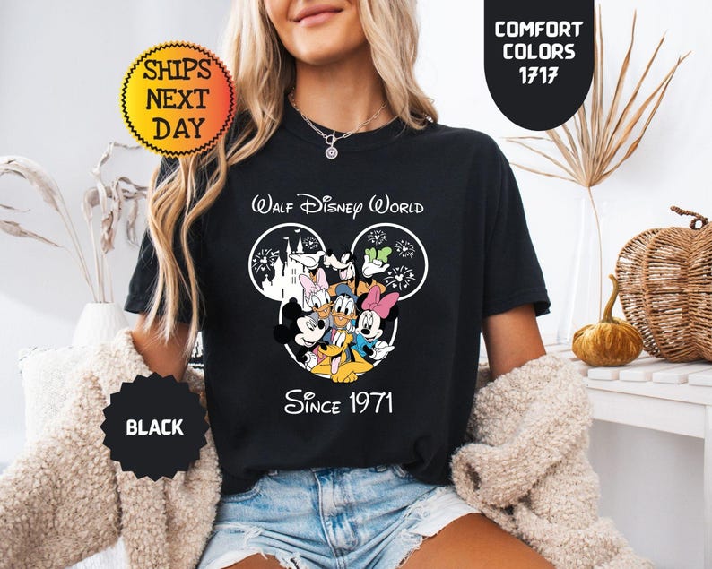 Pode incluir: T-shirt preto com um gr&aacute;fico do Walt Disney World com Mickey Mouse, Pato Donald, Minnie Mouse e Pateta. A camisa tem o texto "Since 1971". A camisa tamb&eacute;m tem o texto "Comfort Colors 1717".