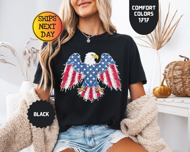 May include: Black t-shirt featuring a patriotic design of an American bald eagle with the US flag incorporated into the wings. The shirt has the text "Comfort Colors 1717" and "Ships Next Day".