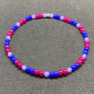 Könnte beinhalten: Ein Armband mit abwechselnd violetten, blauen und rosa Perlen. Das Armband hat einen silbernen Verschluss.