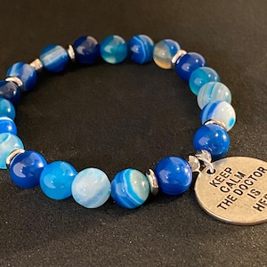 May include: Blue agate beaded bracelet with a silver charm that reads "Keep Calm The Doctor Is Here".
