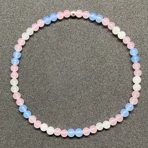May include: A bracelet made of light blue, pink, and white beads with a silver clasp.