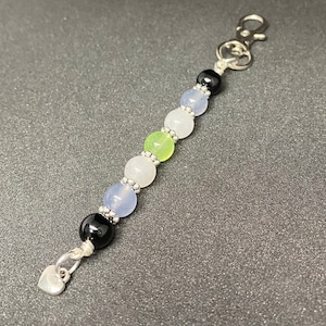 May include: A silver charm bracelet with a heart charm, black beads, and light blue, white, and green beads.