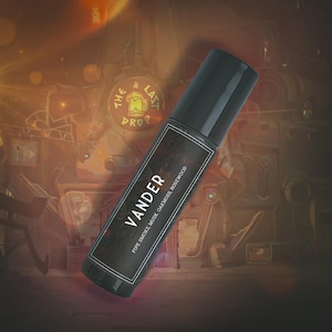 Puede incluir: Un frasco roll-on negro con una etiqueta oscura que muestra el nombre "VANDER" en texto blanco. La etiqueta también enumera "Pipe Smoke, Musk, Oakmoss, Rosewood". El frasco tiene una tapa negra, sobre un fondo borroso de tonos cálidos.