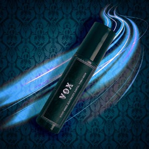 Könnte beinhalten: Eine dunkelgrüne zylindrische Flasche mit schwarzem Deckel. Auf dem Etikett steht "VOX" in silbernen Buchstaben, darunter "BURNT WIRES, ELECTRICITY, SANTAL, TONKA BEAN". Der Hintergrund zeigt ein blaues Blumenmuster und blaue und weiße Lichtstreifen.