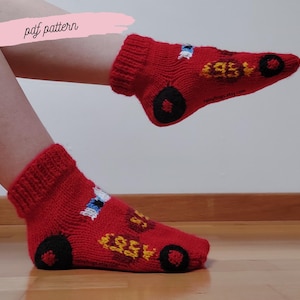 May include: Red knitted socks with a car design. The socks feature black wheels, yellow and white embroidered details, and the text "95". The socks are a cozy and playful accessory.