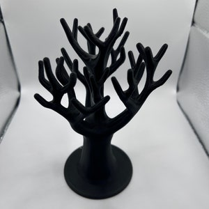 May include: Black tree-shaped jewelry stand with multiple branches for displaying rings, earrings, or necklaces.
