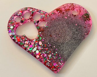 May include: Pink heart-shaped resin ornament with a paw print design and glitter embedded in the resin.