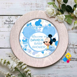 May include: A blue and white baby shower party plate with a Mickey Mouse character wearing a blue onesie. The plate says "Welcome to David's Baby Shower".
