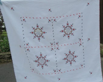 Può includere: Tovaglia bianca con disegni floreali ricamati in rosso e nero. La tovaglia è quadrata e decorata con quattro grandi motivi floreali intricati.