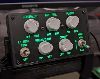 May include: A black control panel with multiple knobs and switches. The panel has labels for "Consoles", "Inst Pnl", "Flood", "Lt Test", "Warn/Caut", "Chart", "Mode NVG", "Dim", and "Nite/Day".