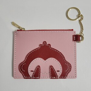May include: A pink leather zippered pouch with a red monkey design and a gold key chain.