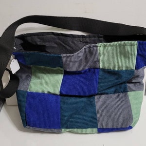以下が含まれることがあります： 青、緑、グレーのコーデュロイ生地で作られたパッチワークトートバッグ。バッグには黒いショルダーストラップが付いています。