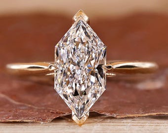 May include: A gold engagement ring with a large, clear, marquise-shaped diamond.