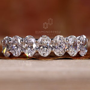 May include: A white gold eternity band featuring a row of seven oval-shaped diamonds.