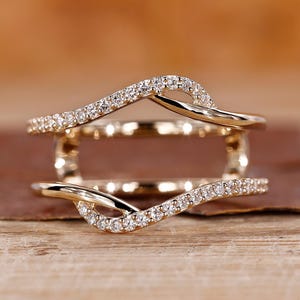 Może przedstawiać: Złoty pierścionek o delikatnym, falistym wzorze. Pierścionek jest ozdobiony małymi, błyszczącymi diamentami.