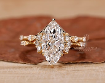 May include: A gold engagement ring featuring a large marquise-shaped diamond centre stone surrounded by smaller diamonds. The ring is set on a delicate band with a matching wedding band.