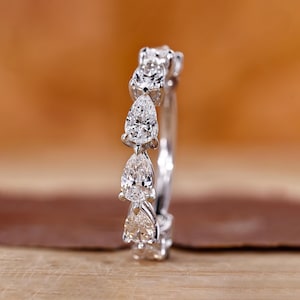 May include: A pear-shaped diamond eternity band with a silver setting. The band features a row of pear-shaped diamonds set in a continuous line.