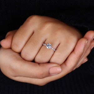 Elegant lady's hand gracefully presenting a Lab Created Diamond Engagement Ring, featuring a unique Marquise and Round Pave Band