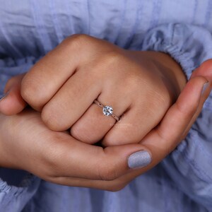 Close-up of an engagement ring with a dazzling centerpiece, nestled amongst Halloween jewelry with ghostly charms