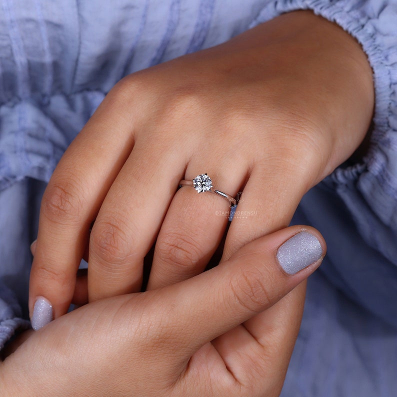 Delicate wedding ring with intricate design details, placed adjacent to wrapped Christmas gifts, hinting at the festive season's joy.
