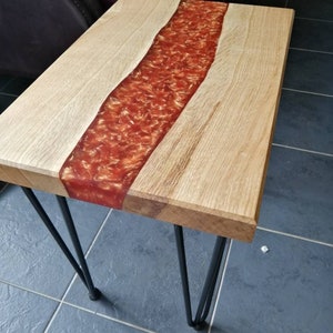 May include: A wooden table with a red resin river running down the center. The table has black hairpin legs.