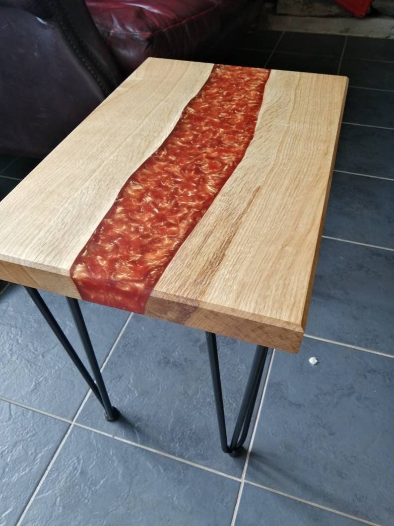 May include: A wooden table with a red resin river running down the center. The table has black hairpin legs.
