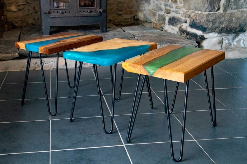 May include: Three wooden side tables with black hairpin legs. The tabletops feature a river of blue, teal, and green epoxy resin.