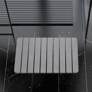 May include: A gray rectangular bath mat with a textured surface. The mat is placed on a black tiled floor.