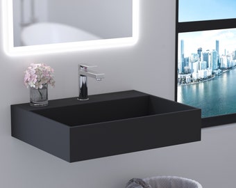 May include: A black rectangular vessel sink with a chrome faucet mounted on the wall. A small vase with pink flowers sits on the counter next to the faucet.