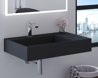 May include: A black wall-mounted bathroom sink with a chrome faucet and a drain pipe. A vase with pink flowers sits on the counter.