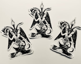 May include: Three black and white stickers featuring a detailed illustration of a winged, horned figure with a pentagram. The figure is sitting on a rock with flames and a crescent moon behind it. The text "Eliphas Levi Occ" is printed below the figure.
