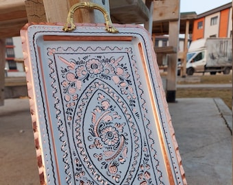 May include: A white metal serving tray with a copper rim and two gold handles. The tray has a decorative floral design in black and copper.