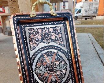 May include: A copper serving tray with black and copper floral designs. The tray has two gold handles.