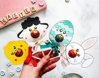 May include: Three Easter-themed lollipop crafts, featuring a chick, a bunny, and an egg, each with a round lollipop attached to the face. The lollipops are red, white, and blue.