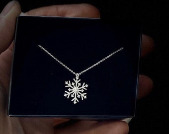 May include: A silver snowflake pendant necklace in a black velvet box.