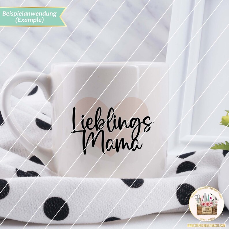 K&ouml;nnte beinhalten: Wei&szlig;e Keramiktasse mit einem rosa Herzen und dem Text "Lieblings Mama" in schwarzen Buchstaben.