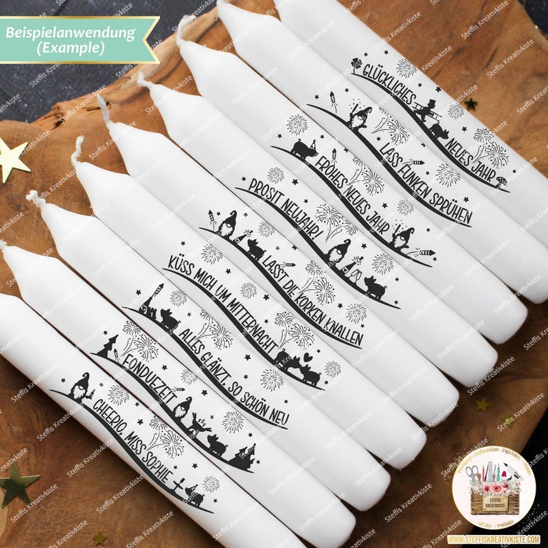 May include: Ten white candles with black ink designs and German text. The text on the candles includes "Gl&uuml;ckliches Neues Jahr", "Lass Funken Spr&uuml;hen", "Frohes Neues Jahr", "Prosit Neujahr", "Lasst die Korken Knallen", "K&uuml;ss mich um Mitternacht", "Alles gl&auml;nzt, so sch&ouml;n neu", "Fonduezeit", and "Cheerio, Miss Sophie".