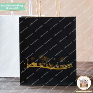 May include: Black paper gift bag with gold lettering that says "Alles gl&auml;nzt so sch&ouml;n neu" and a gold illustration of fireworks, a bottle of champagne, and two pigs. The bag has a brown paper handle.