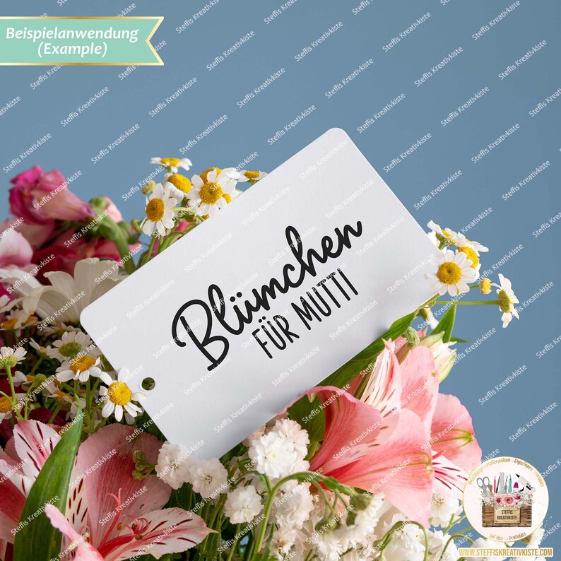 May include: A white card with black text that reads "Bl&uuml;mchen f&uuml;r Mutti" (Flowers for Mom) is placed in a bouquet of white and pink flowers.