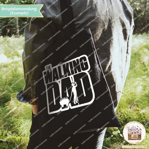 Op de afbeelding: Een zwarte tote bag met een witte afbeelding waarop "The Walking Dad" staat met een silhouet van een persoon die een kruiwagen duwt.