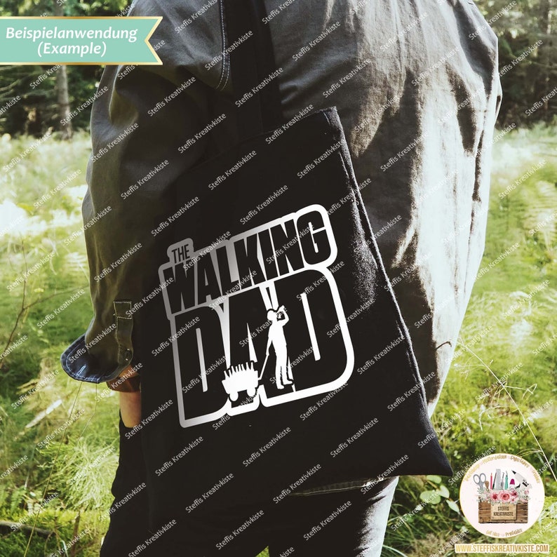 Op de afbeelding: Een zwarte tote bag met een witte afbeelding waarop "The Walking Dad" staat met een silhouet van een persoon die een kruiwagen duwt.