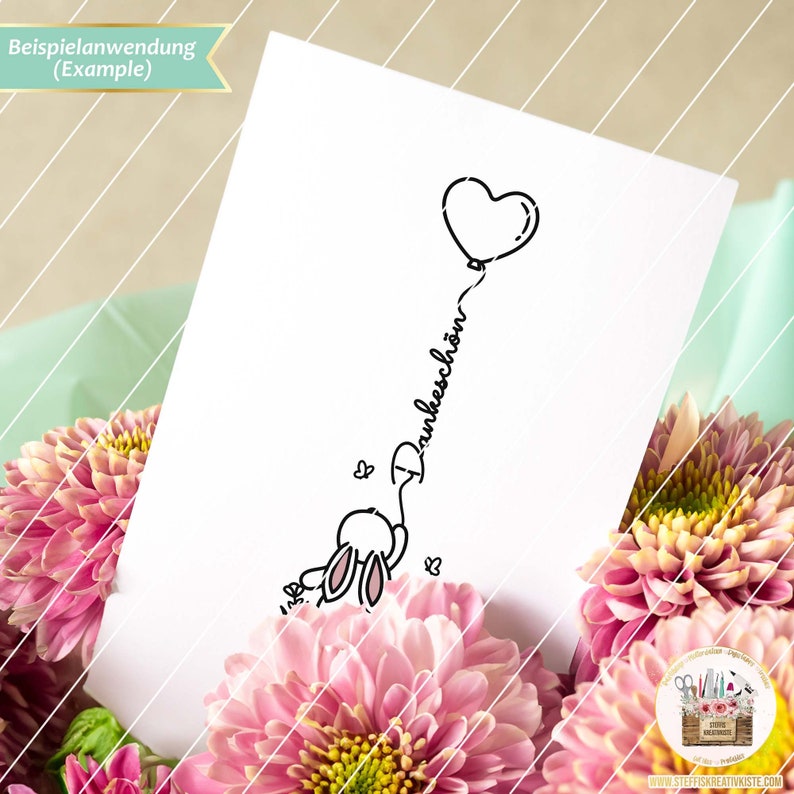 May include: A black and white line drawing of a bunny holding a heart-shaped balloon with the word "Dankesch&ouml;n" written on the string.