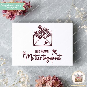 May include: A white card with a brown stamp featuring a floral design inside an envelope. The text "HIER KOMMT Muttertagspost" is below the stamp.