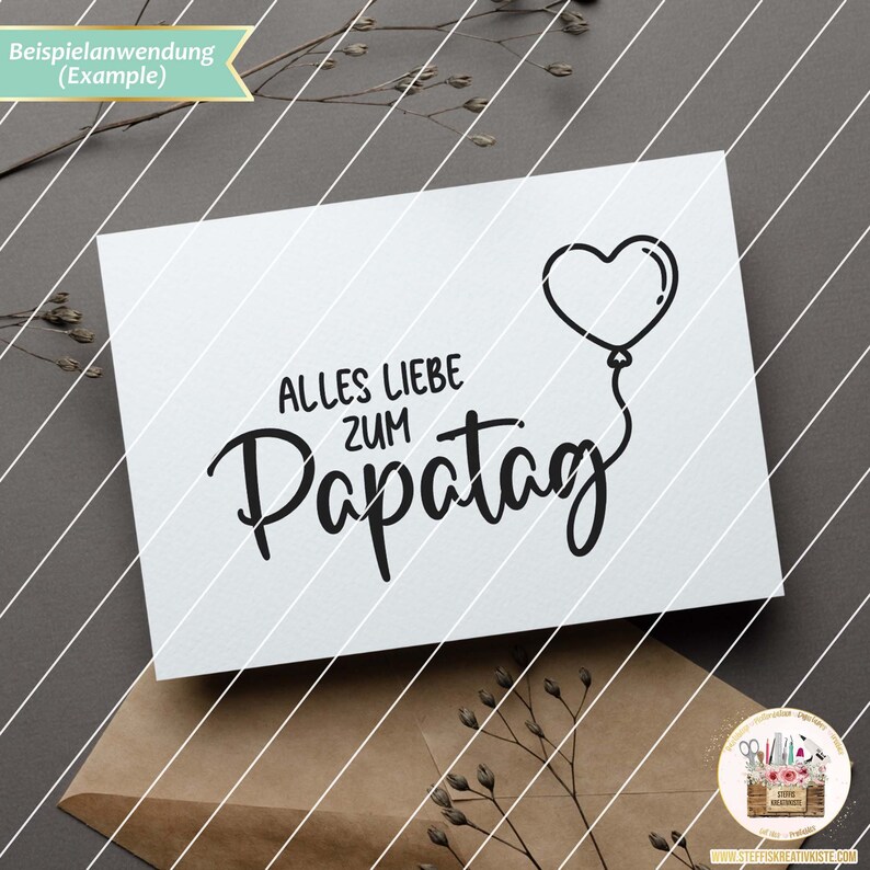 May include: A white card with black text that reads "Alles Liebe zum Papa Tag" with a heart-shaped balloon above the text.