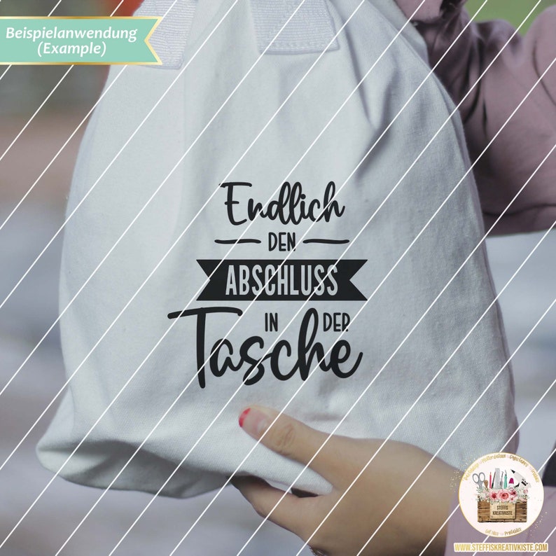 May include: White canvas tote bag with black text that reads "Endlich den Abschluss in der Tasche".