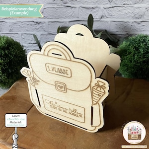 May include: A wooden cutout of a backpack with the text "1. KLASSE" and "Fur einen tollen Start in die Schule" on it. The backpack is made of light brown wood and has a heart shape on the front. The cutout is a craft project for a laser cutter.