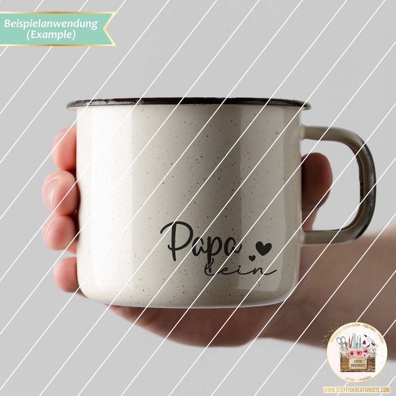 May include: White enamel mug with a black handle and a black inscription that reads "Papa  ein" with two small black hearts.