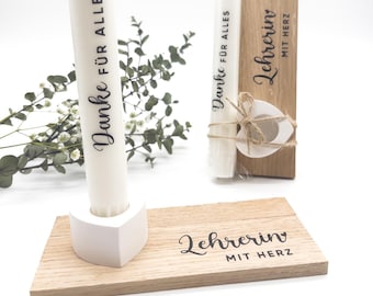 May include: Two wooden plaques with the text "Danke für alles" and "Lehrerin mit Herz" on them. One plaque has a white candle with the same text on it. The other plaque has a white heart with a twine bow.