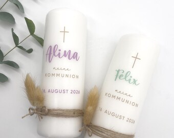 May include: Two white candles with gold crosses and the names Alina and Felix written in purple and green. The text "meine Kommunion" and the date "16. August 2026" are written on each candle.