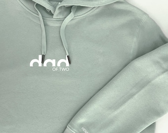 May include: A light green hooded sweatshirt with the text "dad of two" in white lettering on the front. The text "Henry & Leni" is printed on the sleeve.